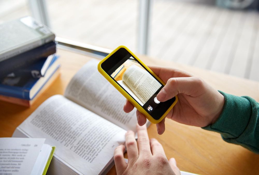 student taking picture for a summary from a textbook