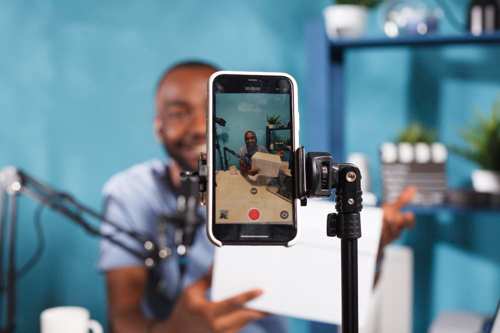man in studio using a phone on a stand to record selfie video
