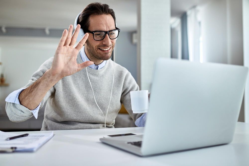 man waving to colleagues on zoom call